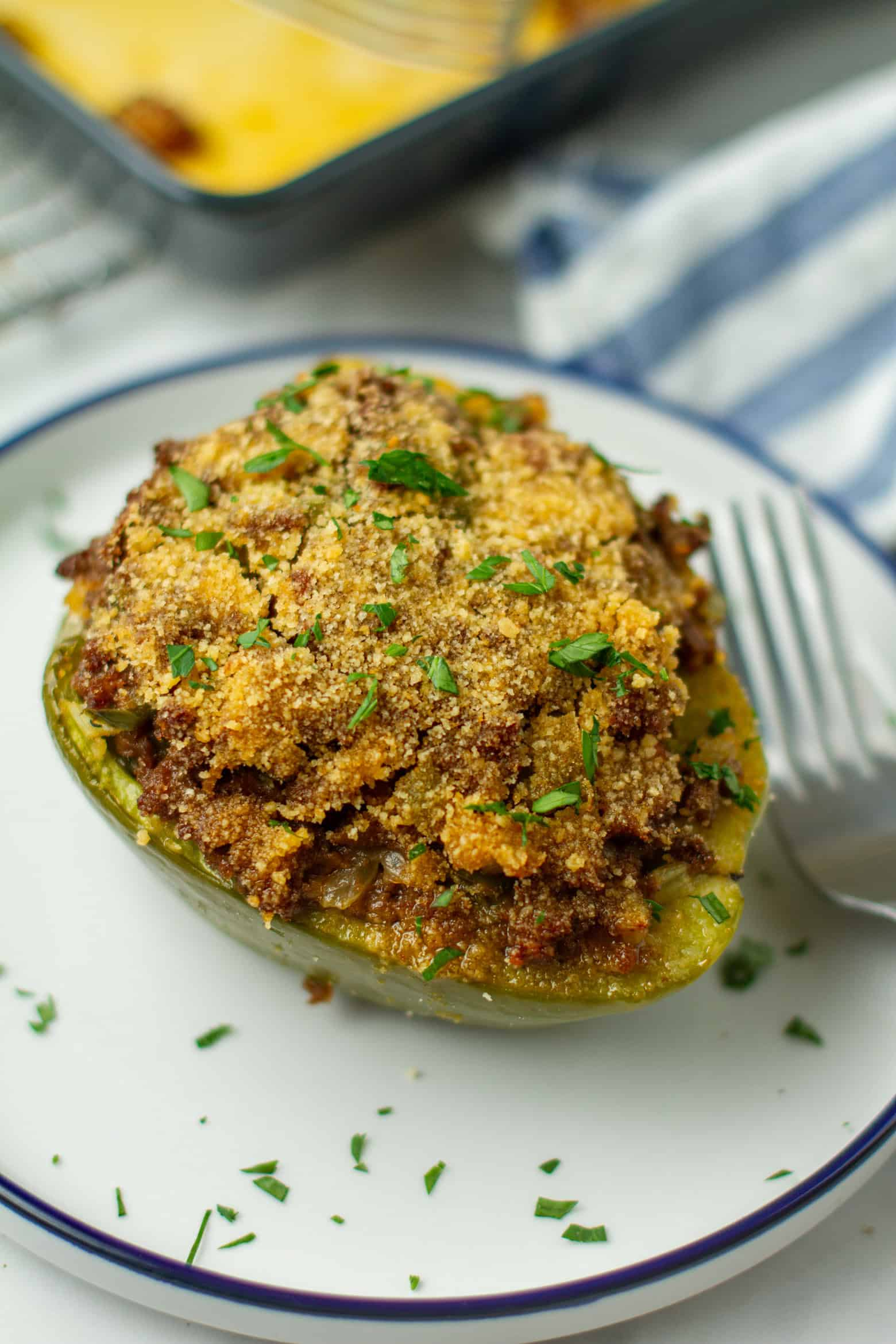 Cajun stuffed bell pepper topped with golden breadcrumbs and fresh parsley on a white plate